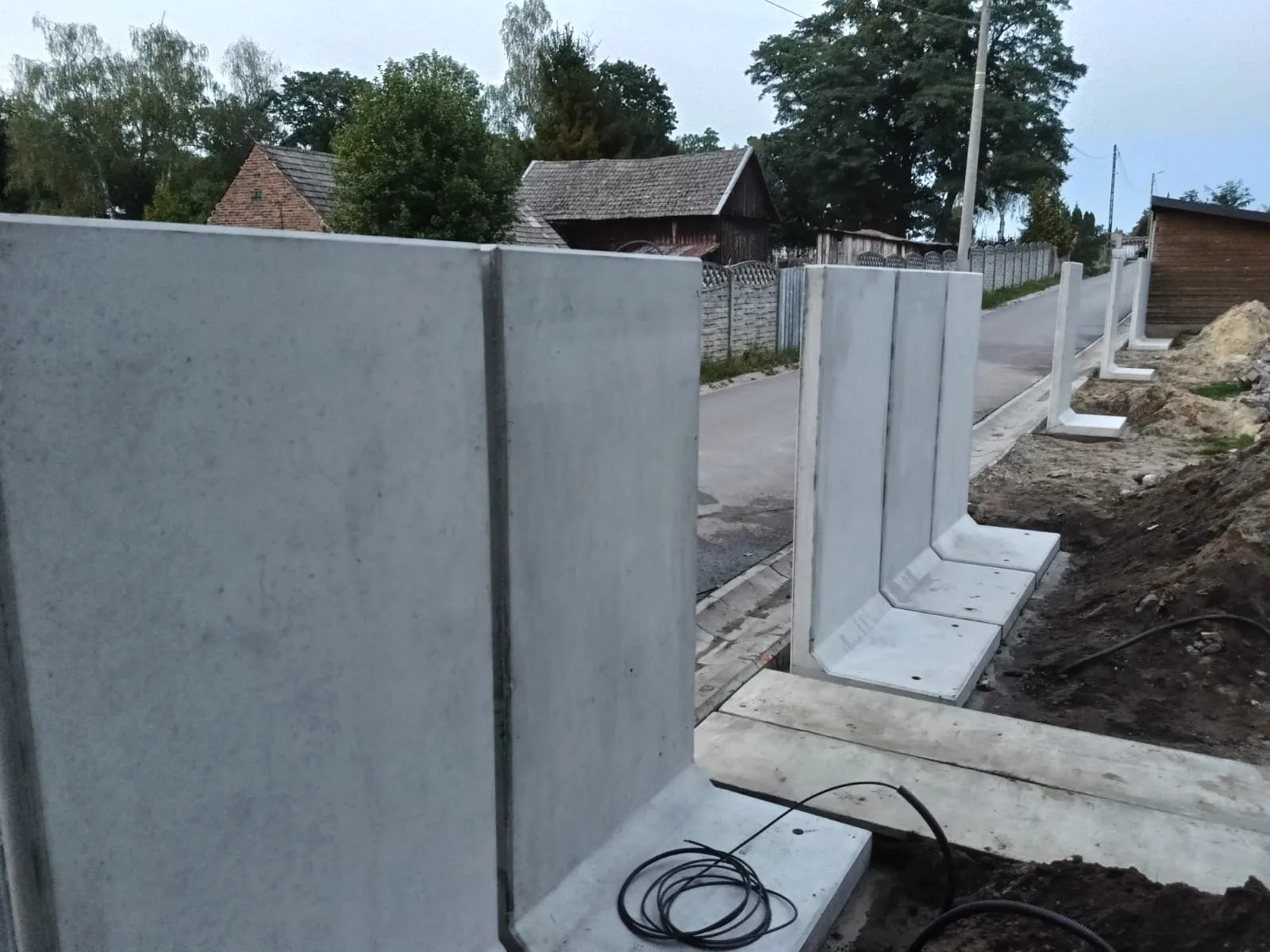 Betonowe elementy o przekroju L ustawione jako ogrodzenie