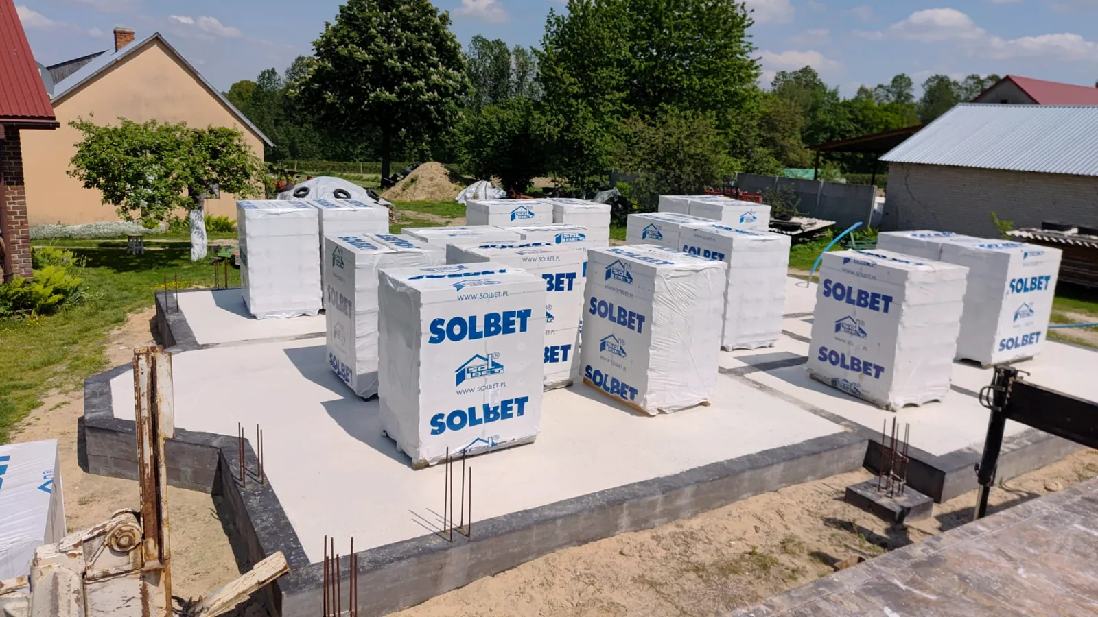 Palety bloczków przy ścianach fundamentowych budowy