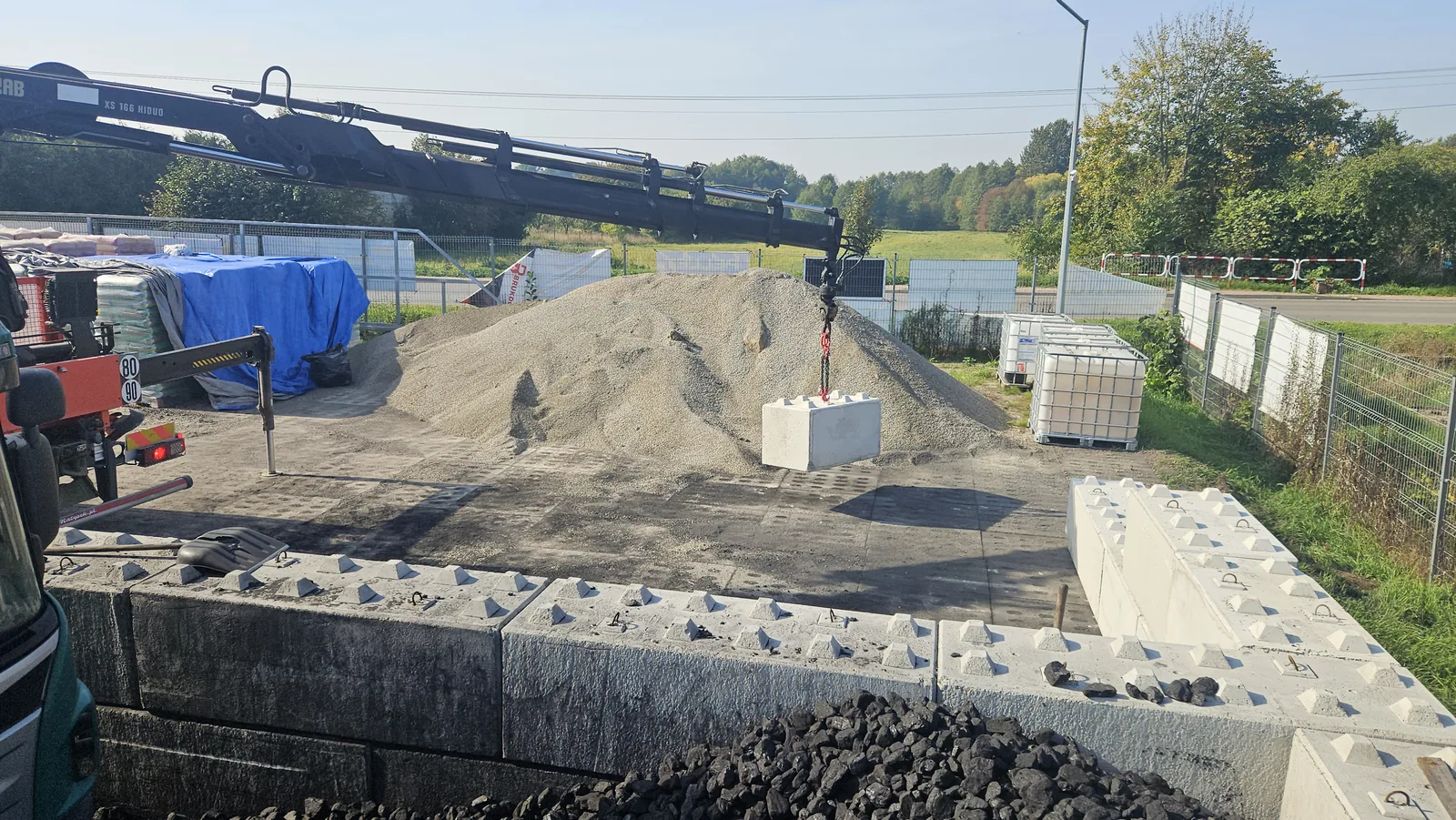 HDS ustawia betonowy element przy boksach na placu Siembida