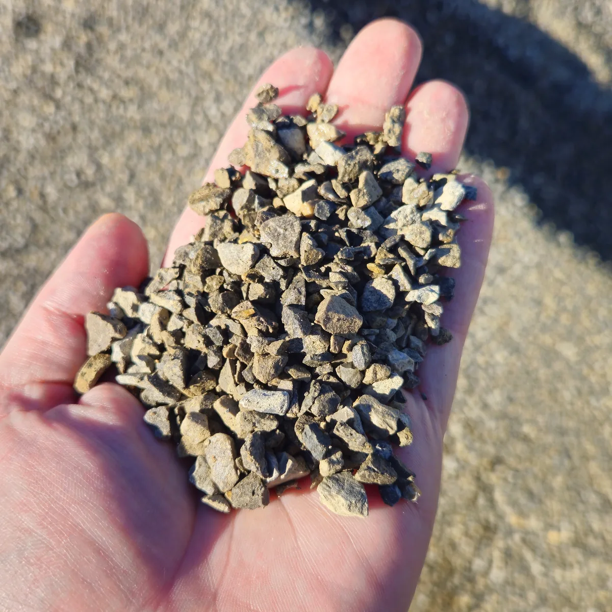 Kruszywo frakcji 2–8 mm na dłoni, na tle pryzmy
